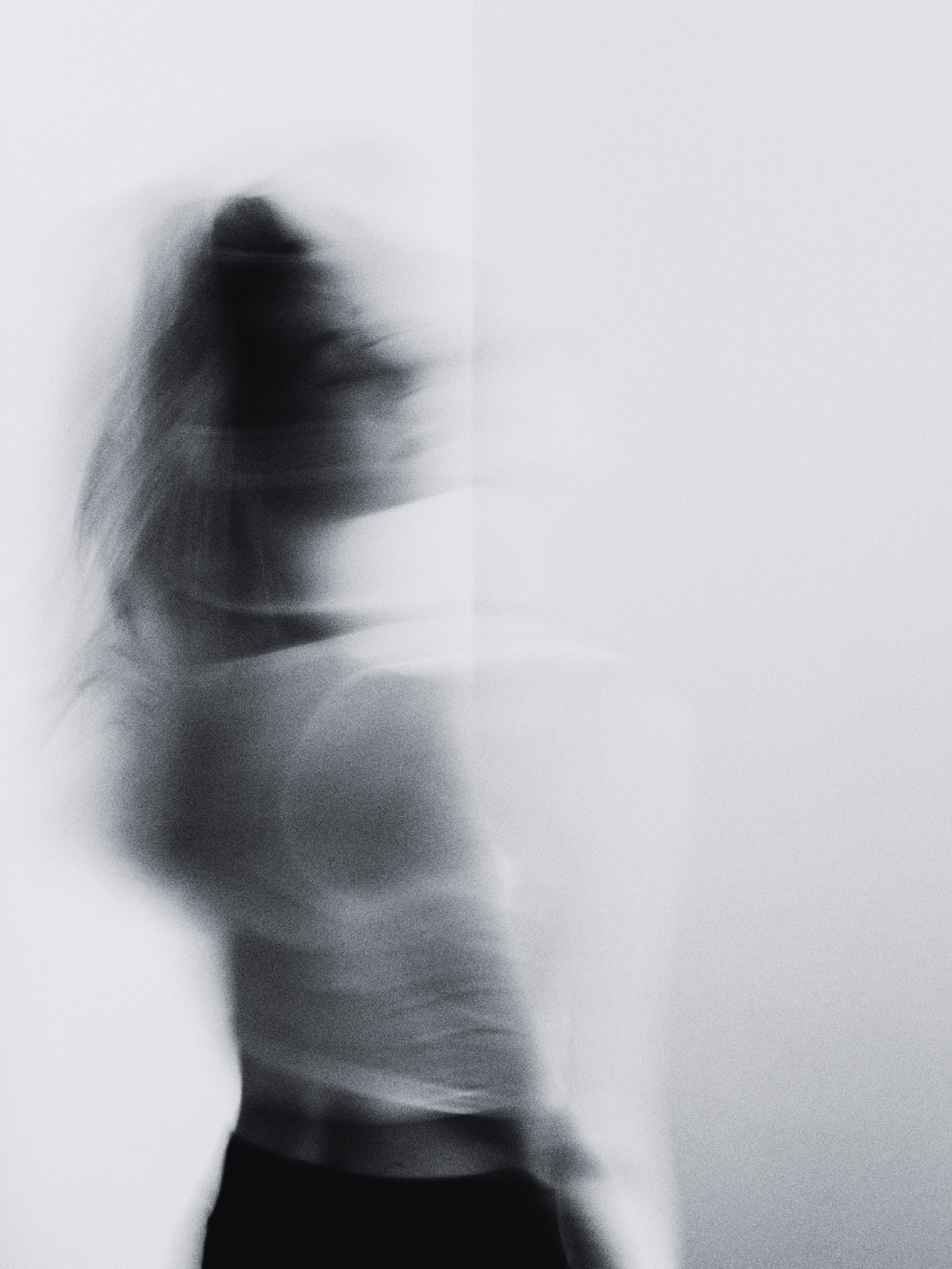 Ghostly blurred black and white image of a woman sitting against a wall — reflecting the hidden emotional signals behind warm leads going quiet, as analyzed by Smith + Soma.