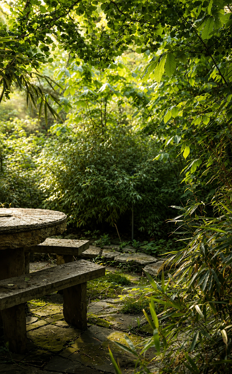 A stone picnic table and benches in a lush green garden with dense foliage and pathway.
