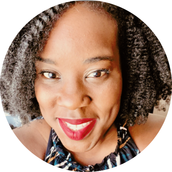 Close-up of a woman smiling with curly hair, red lipstick, and wearing a patterned top.
