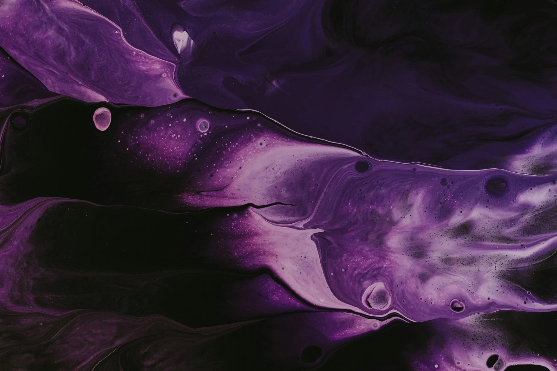 Abstract purple and black swirling fluid art with streaks of white and small bubbles.