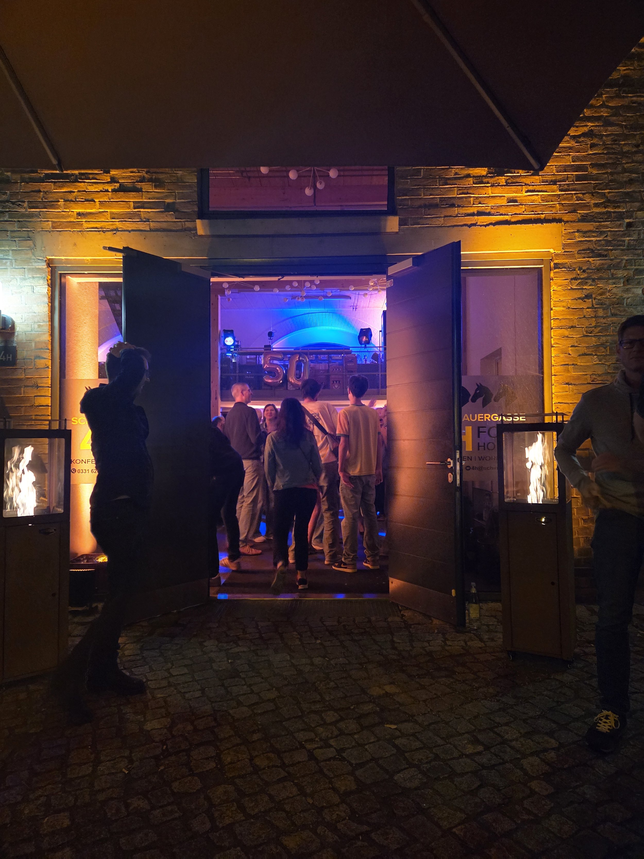Menschen feiern draußen bei Nacht in der Schiffbauergasse vor dem 4Horses.
