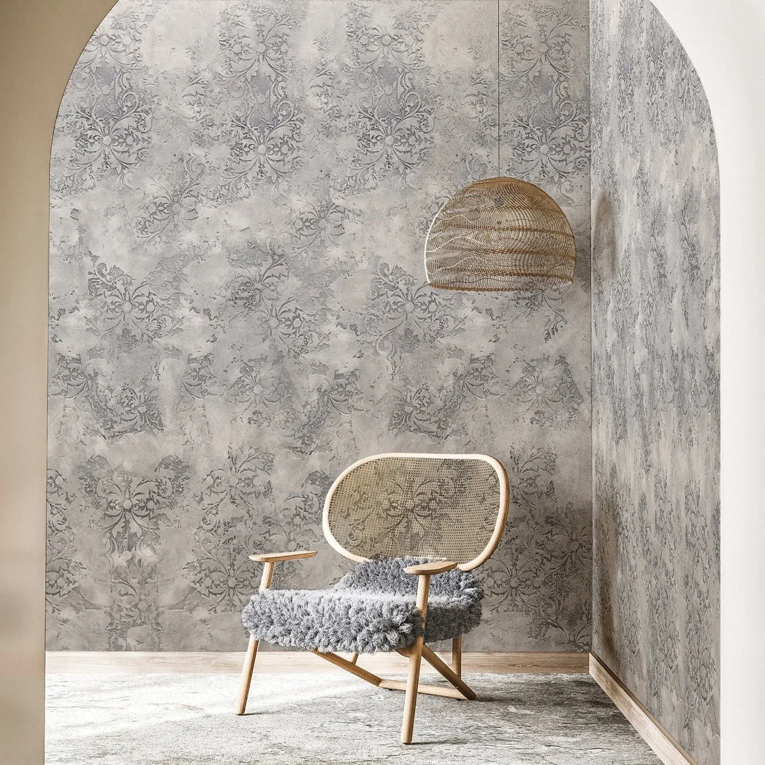 A cozy seating corner with a wooden chair with a furry gray cushion, a textured damask-patterned wall, and a woven pendant light hanging from the ceiling.