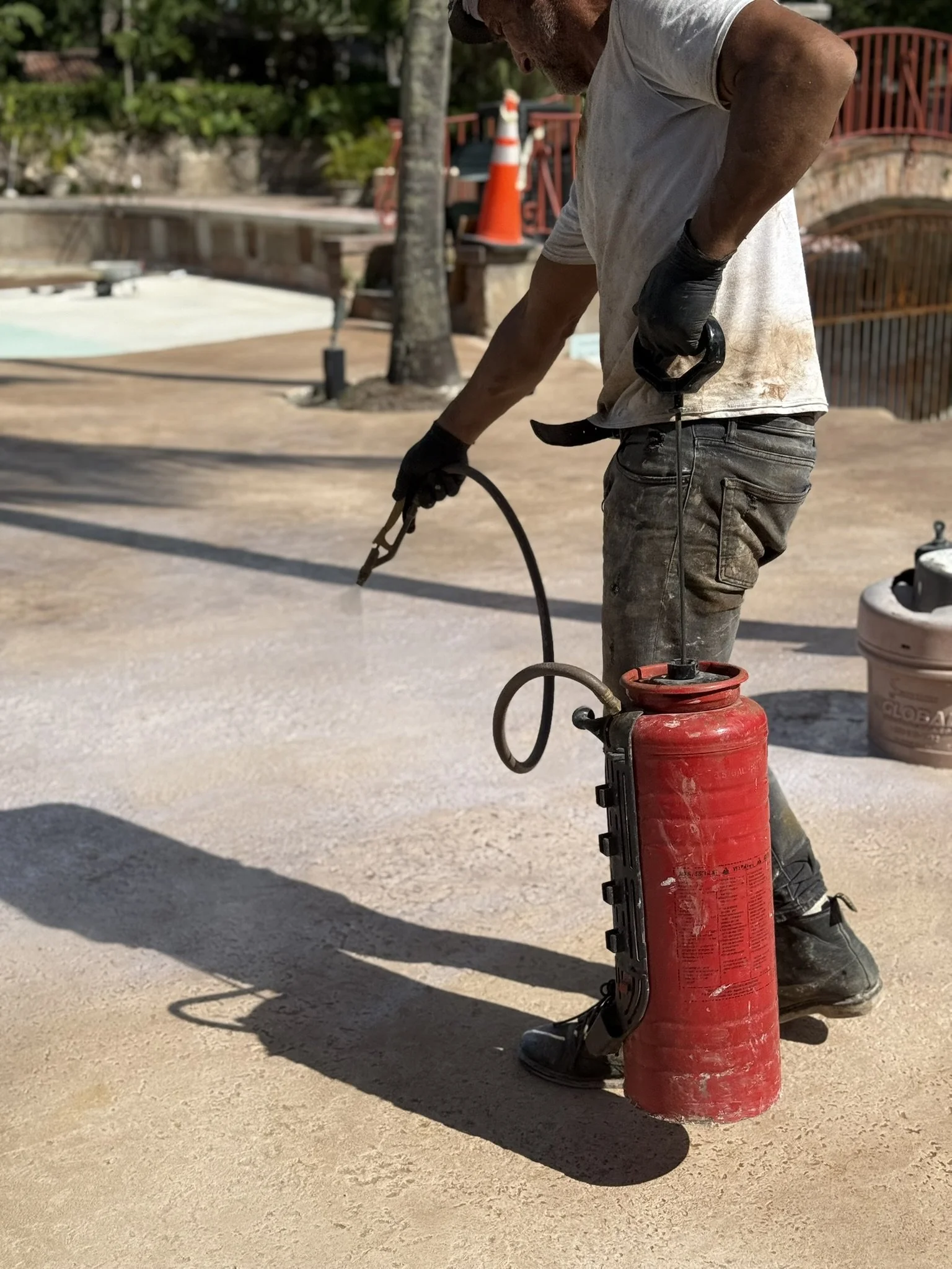 Construction worker using a fire extinguisher on the ground outdoors.