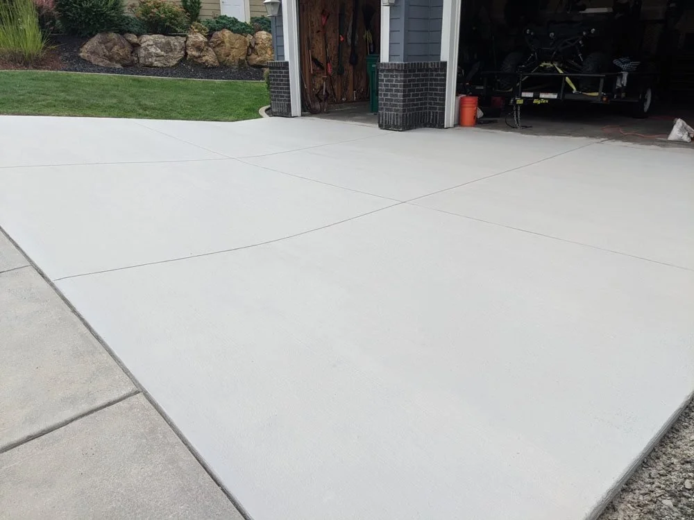 Clean concrete driveway next to a garage with storage and a boat