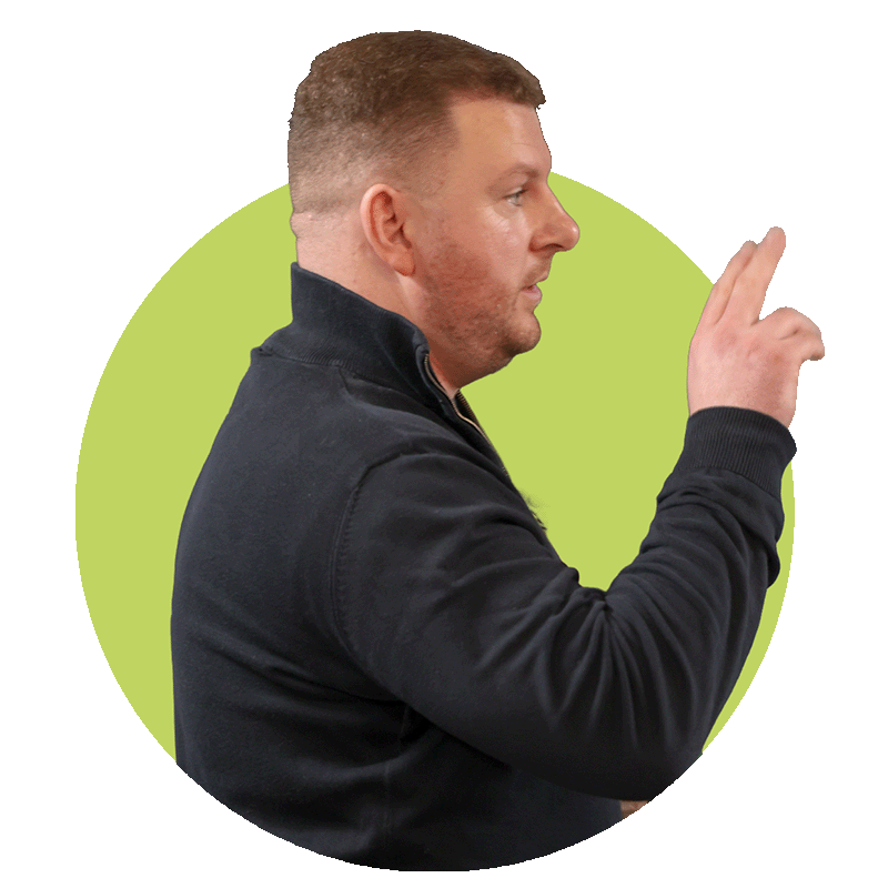Profile view of a man with short hair wearing a black jacket, holding up his right hand with two fingers extended, against a light green circular background.