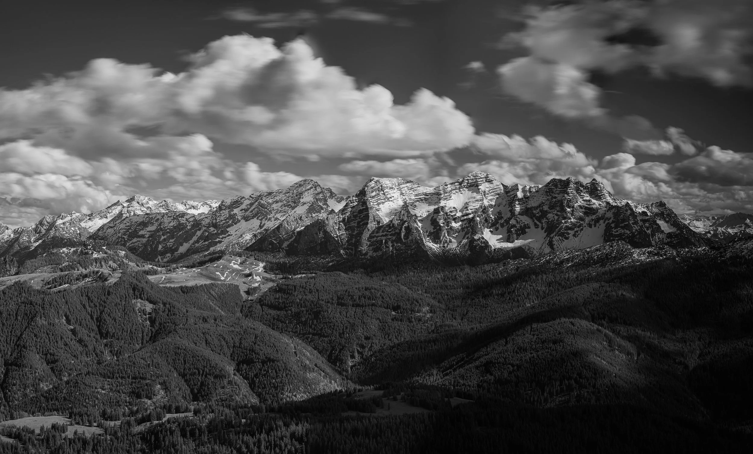 Schneebedeckte Berge unter einem bewölkten Himmel in einer schwarzen und weißen Fotografie.