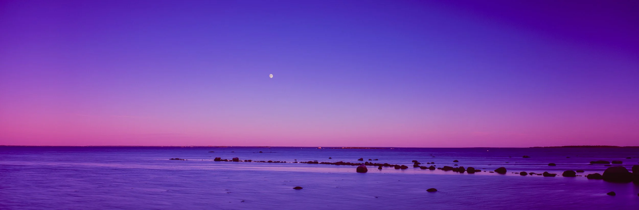Zu sehen ist eine Küstenlandschaft in Schweden die mit einem Fujifilm Velvia im Mittelformat und einer Fujifilm G617 fotografiert wurde. Ein Sonnenuntergang mit schönen Farben in Magenta bis Lila und Rosa, die Landschaft leuchtet unglaublich schön.