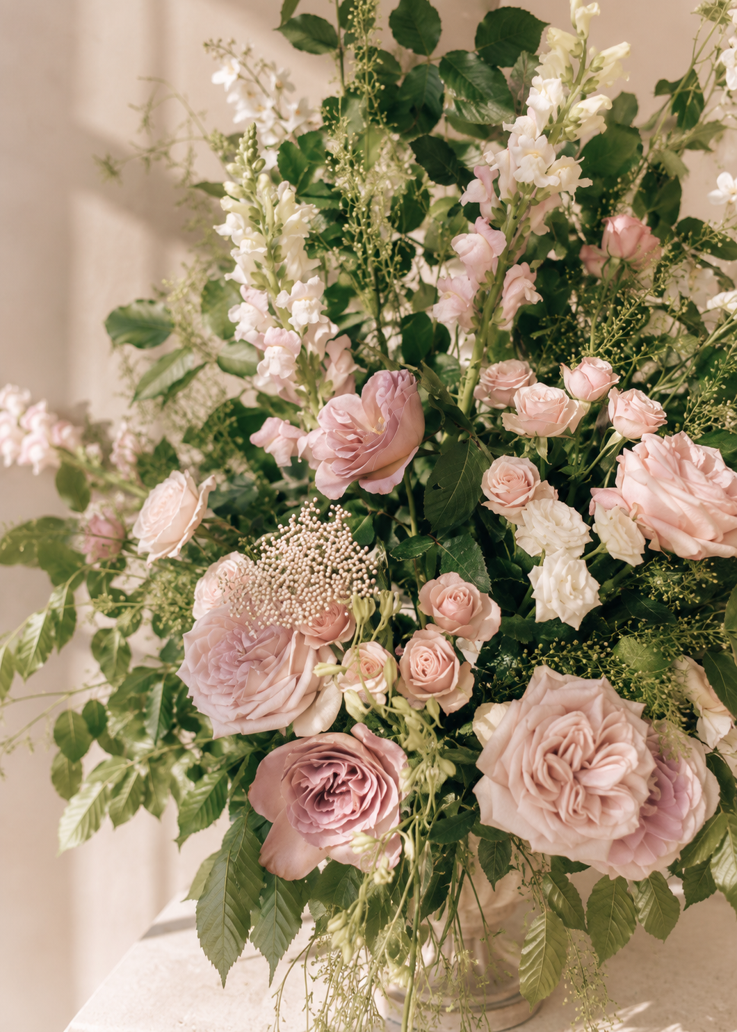 A large floral arrangement with pink roses, white lilies, and greenery in a vase.