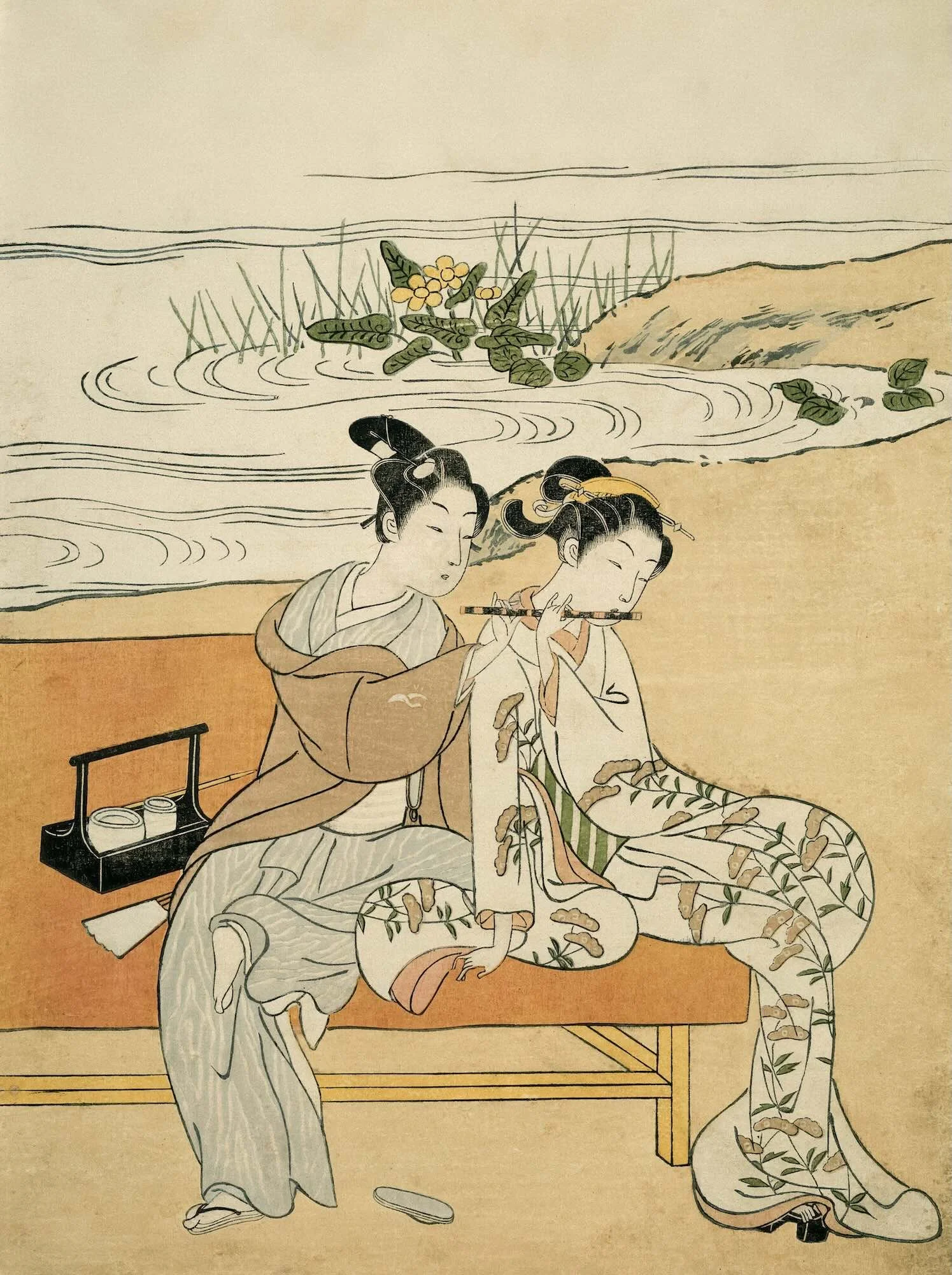 Traditional Japanese scene with two women in kimonos, one standing and one sitting, playing a flute in front of a body of water with plants and rocks, on a tatami mat with a small table.