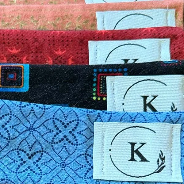 Detail of anti-tarnish silver protector cloths for flutes, in a variety of colors and patterns, with K logo tags.