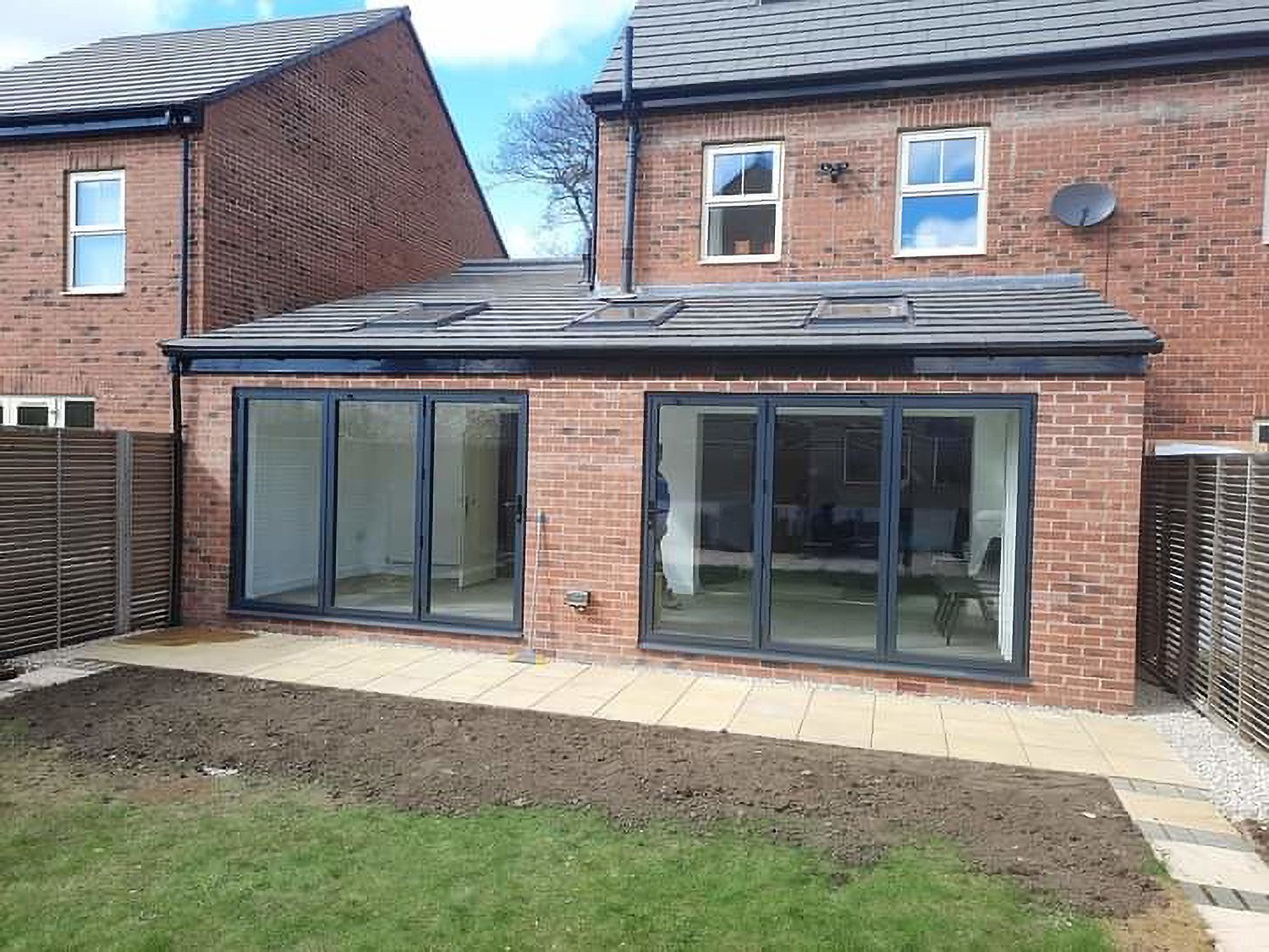 A single story extension at the rear of a residential property with bi-fold doors and sky lights.