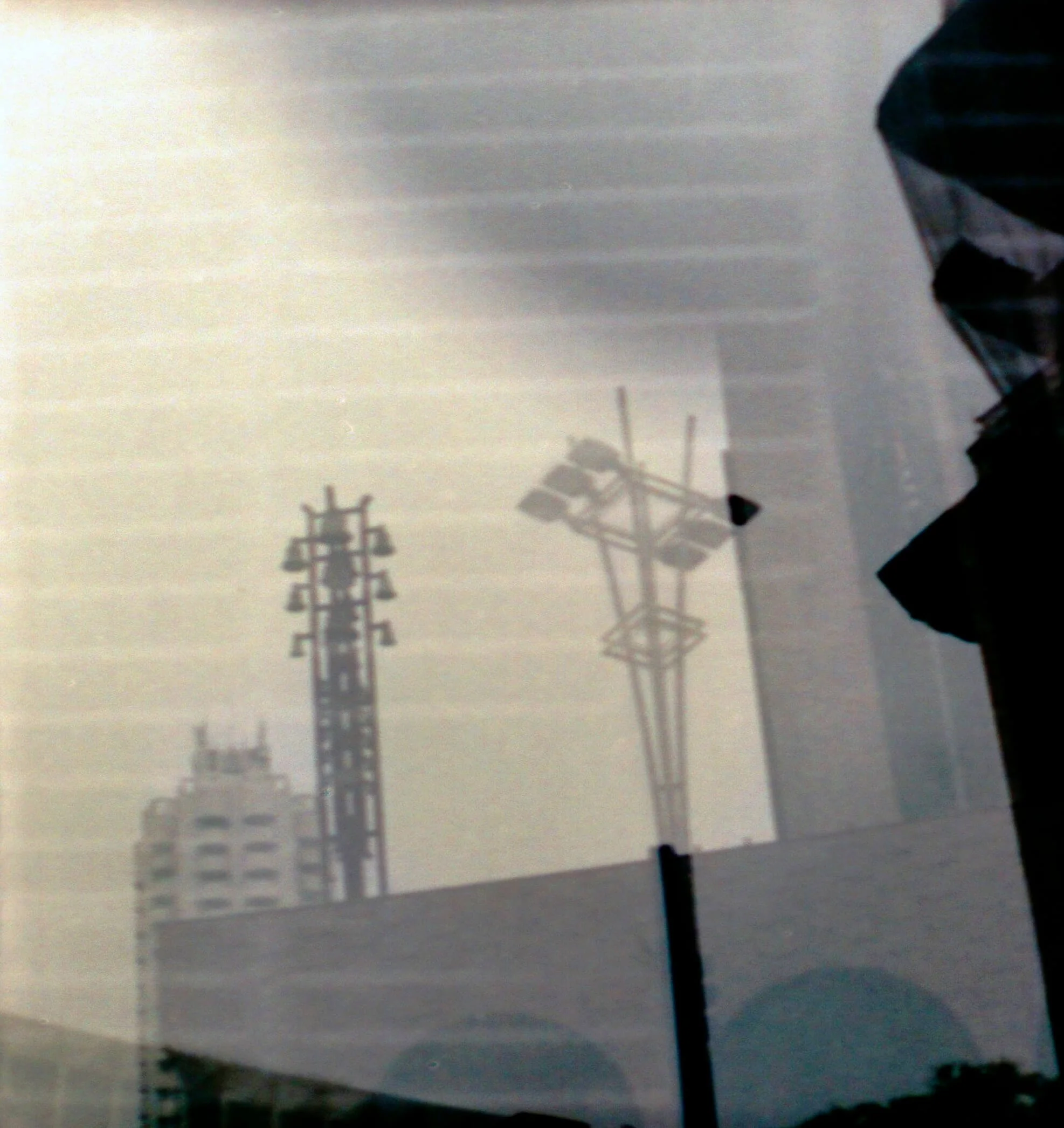 Weathered utility poles with power lines and some additional telecommunications equipment on a cloudy or foggy day.