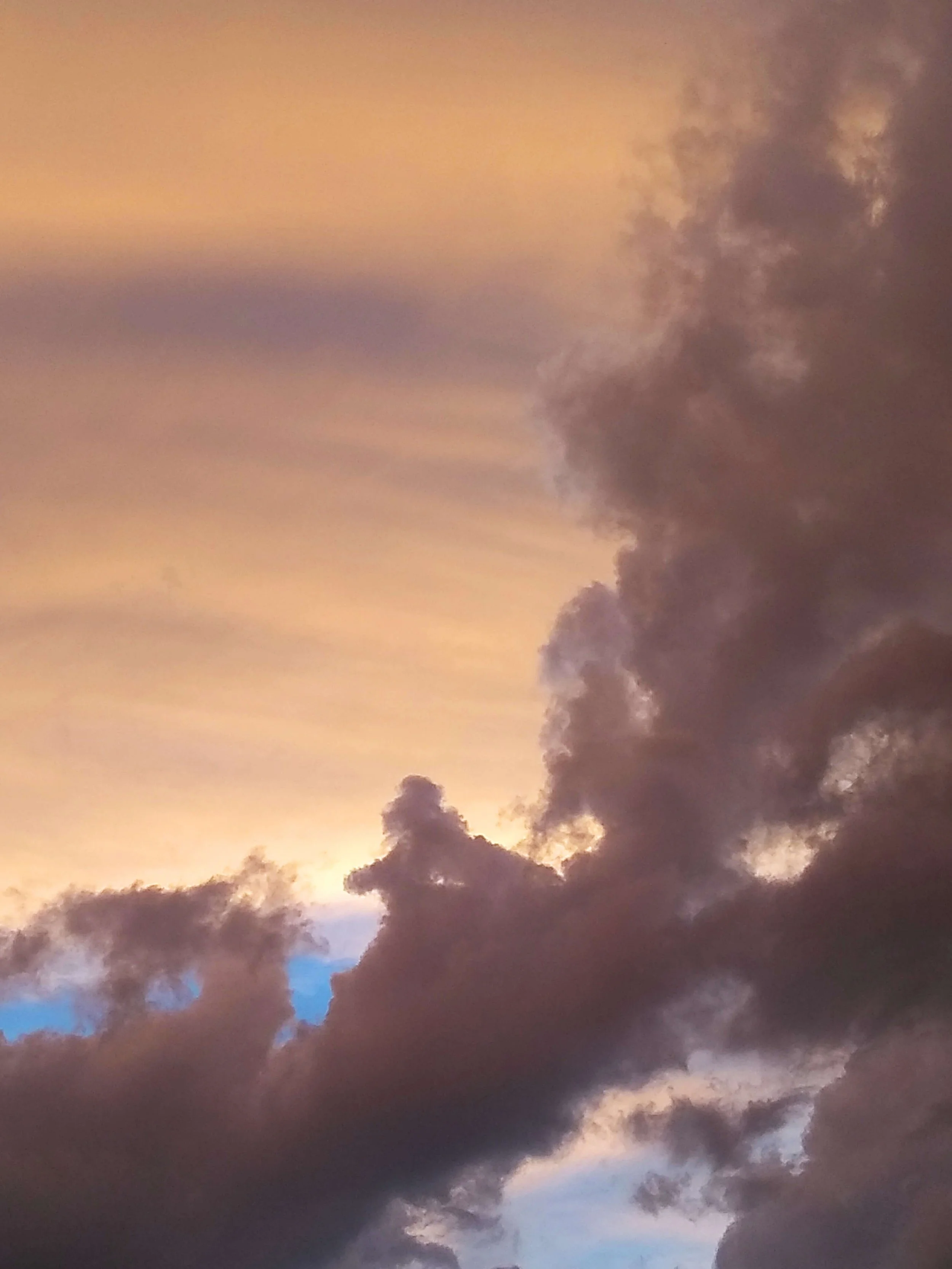 A sky filled with dark clouds with some lighter, pinkish and blue hues, possibly during sunset or dawn.