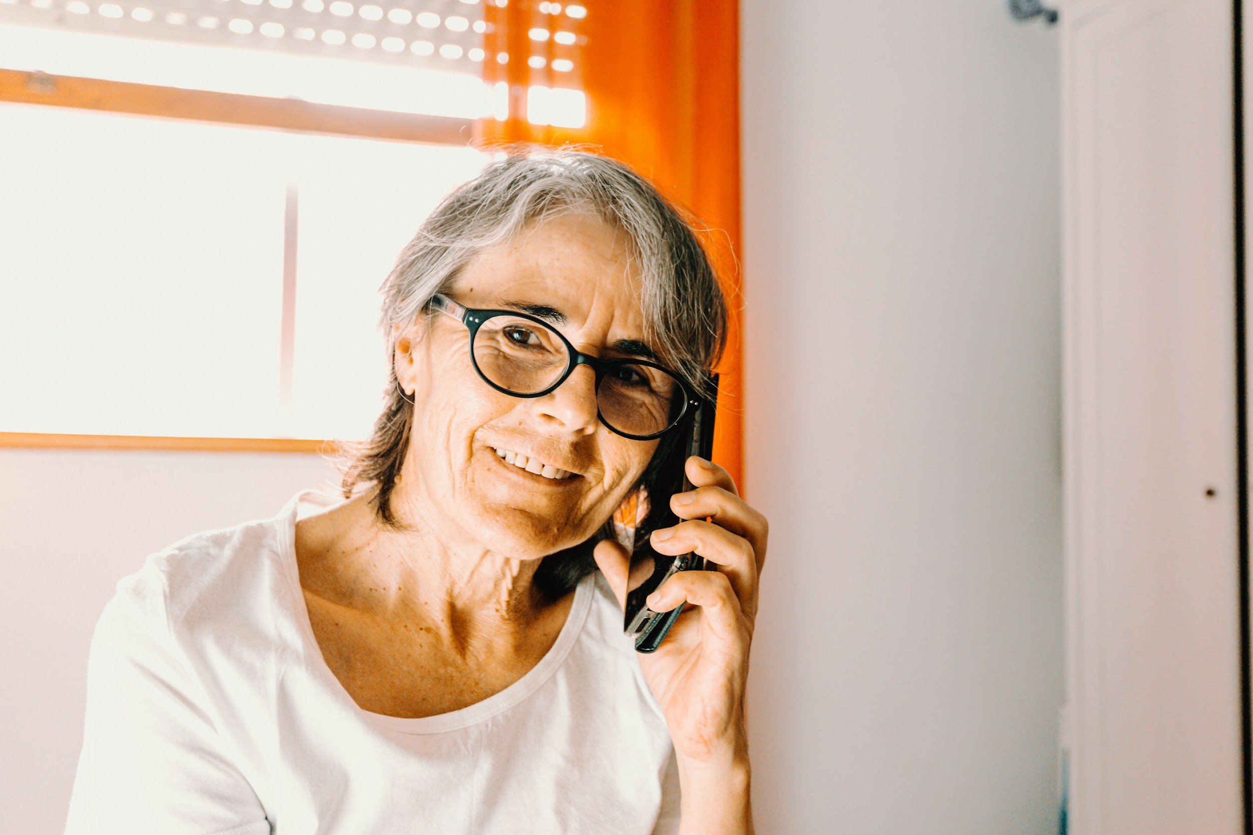 Smiling older woman talking on the phone at home