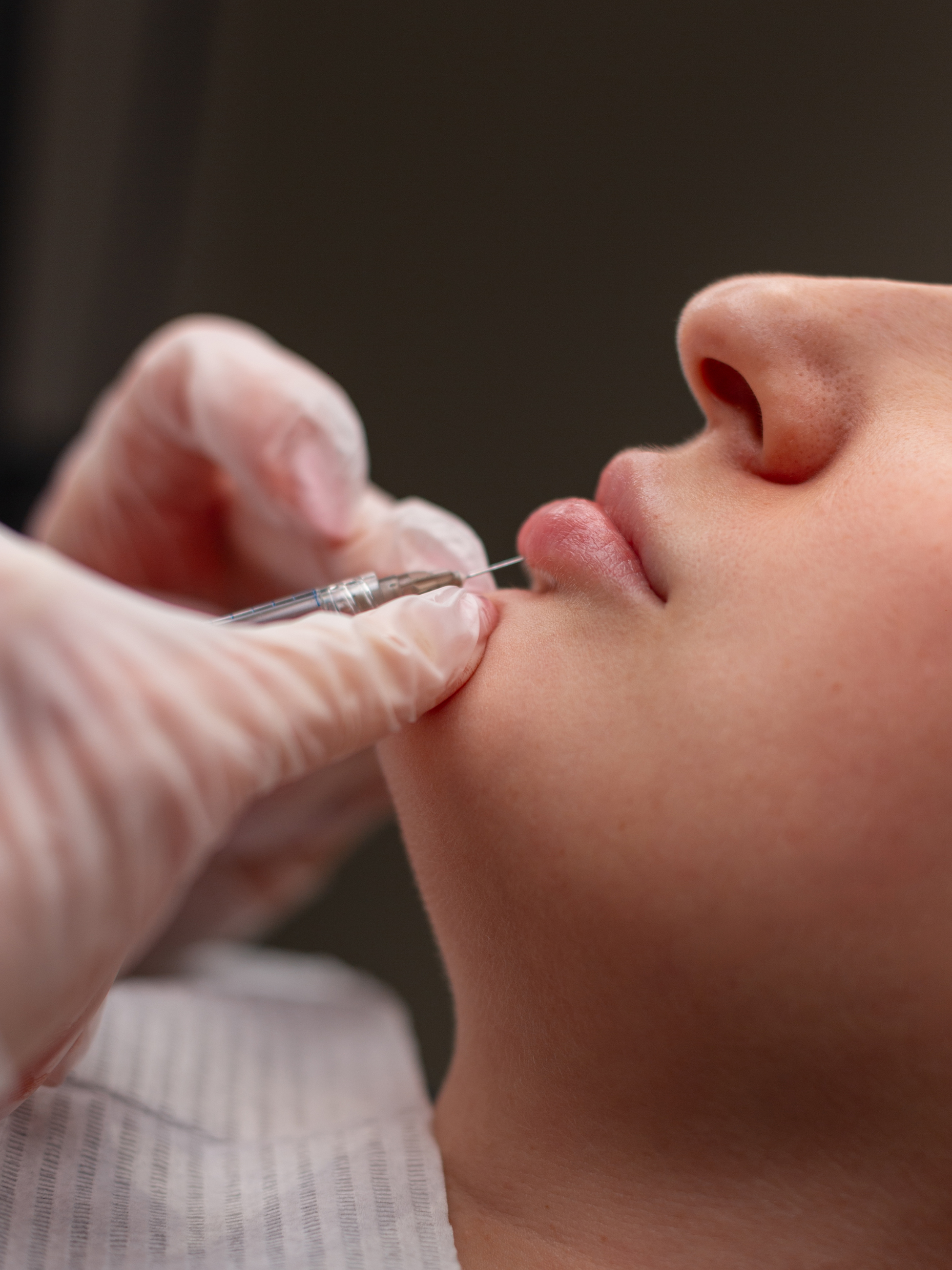Close-up of a person receiving a vaccination shot in their upper arm from a medical professional wearing gloves.