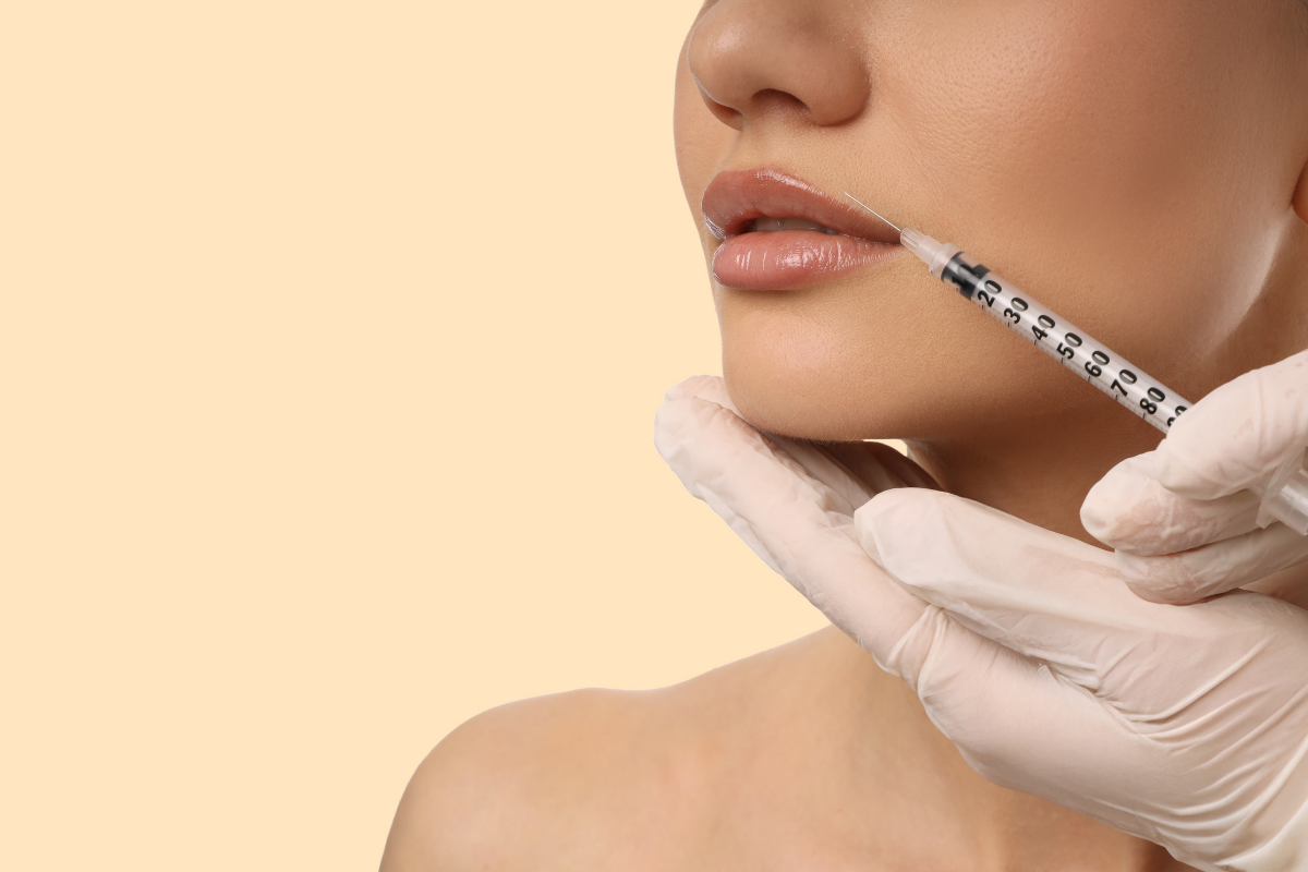 A person receiving a cosmetic injection near their lips, held by a gloved hand.