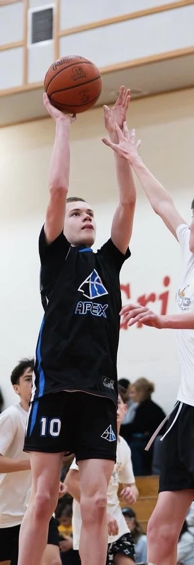 A young male basketball player in a black jersey with the number 10 shooting a basketball.