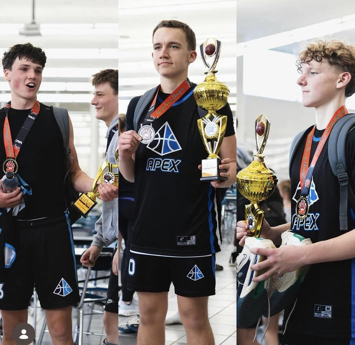 Group of young male athletes wearing black sports uniforms and medals, holding trophies, in a celebration setting.