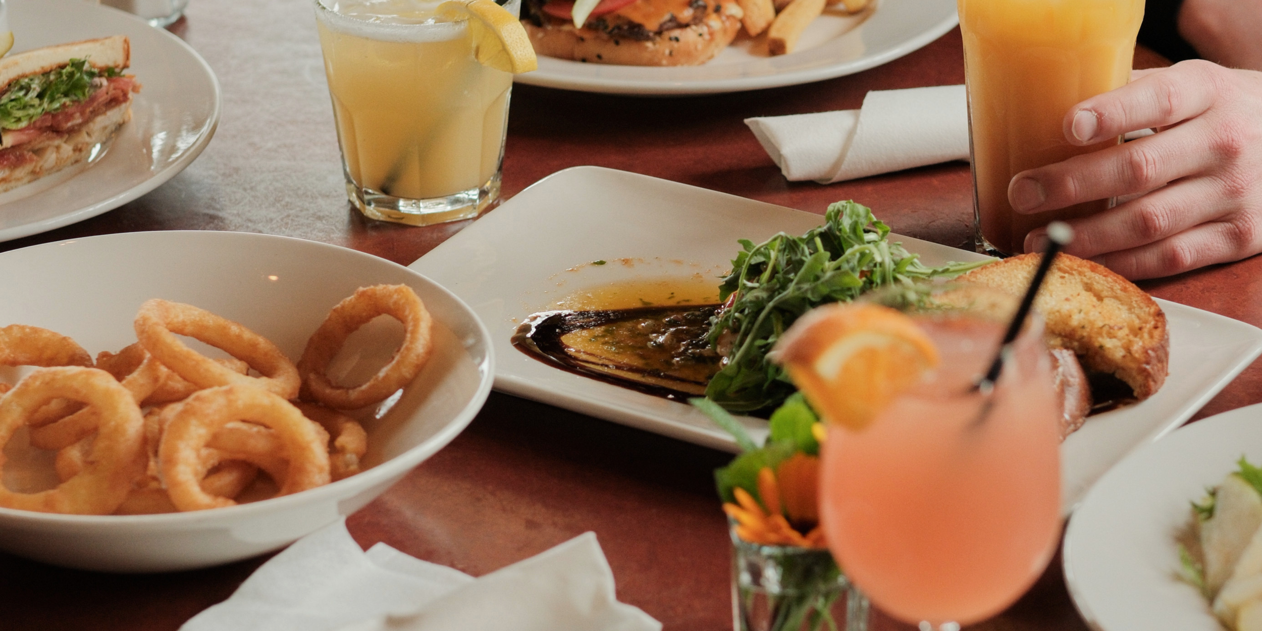 A table filled with various dishes, including onion rings, a plate with meat and vegetables, and drinks at the Salt Spring Inn on Salt Spring Island.