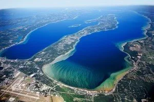 Aerial view of a large crescent-shaped lake with a sandy shoreline and surrounding greenery.