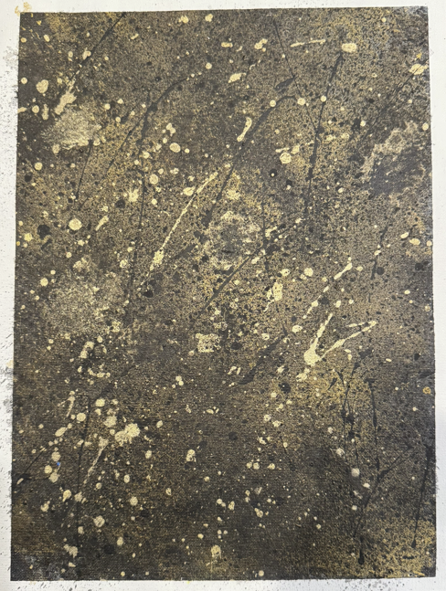 A dark, textured surface with random yellowish paint splatters and streaks.
