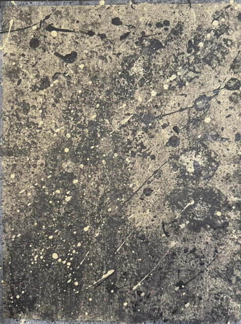 Close-up of a stained, splattered concrete or stone surface with black, white, and gray paint or dye splatters and streaks.