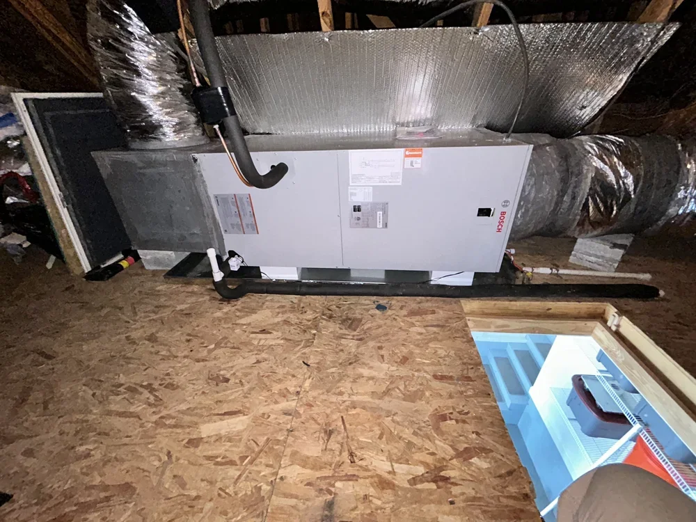 HVAC system installed in an attic space with insulation, ductwork, and a heating or cooling unit.