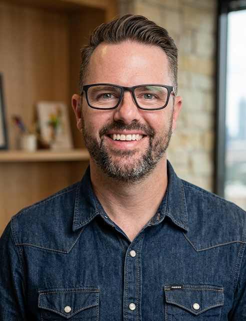 man with glasses in denim shirt smiling