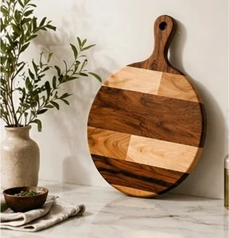 Wooden cutting board with alternating light and dark wood panels leaning against a wall.