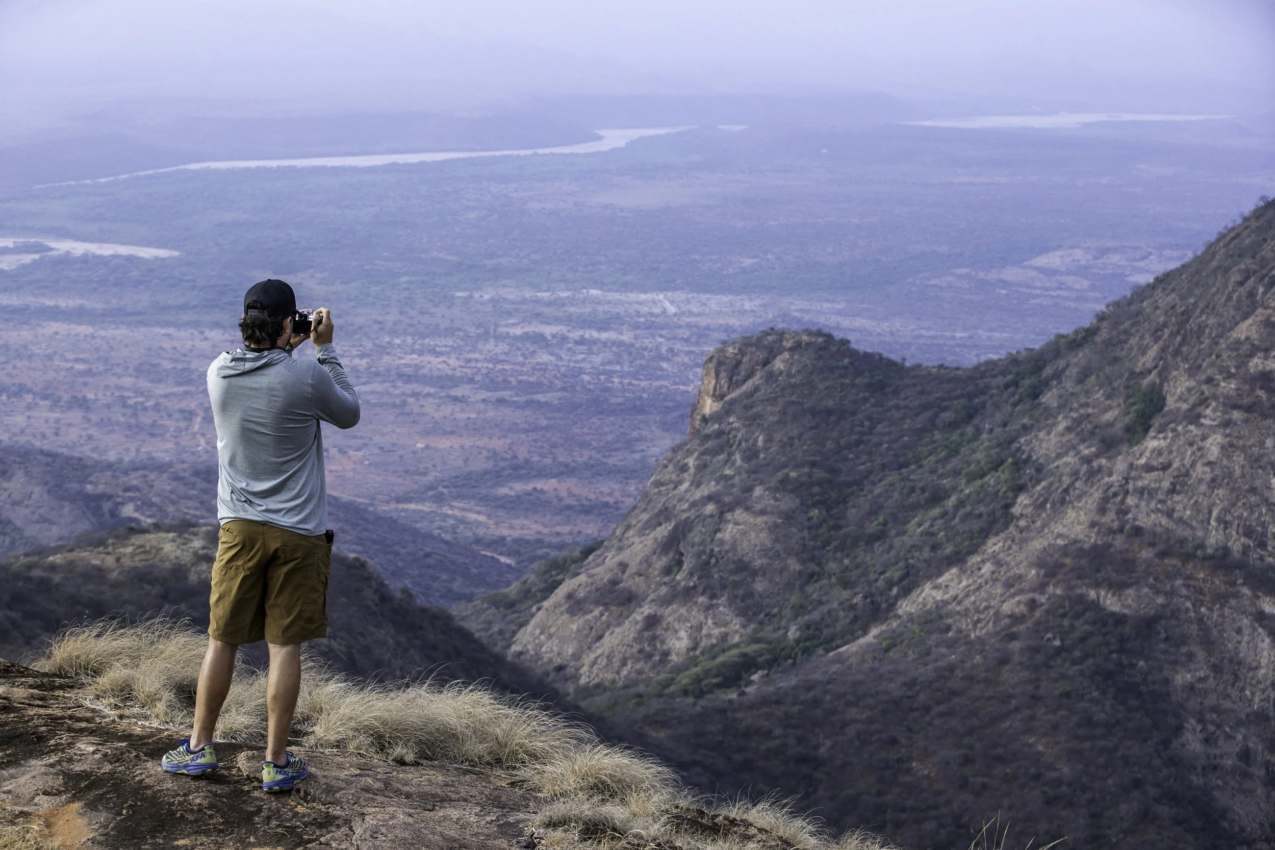 Namunyak Wildlife Conservation Trust A man stands with a camera taking a photo of the wilderness in front of him