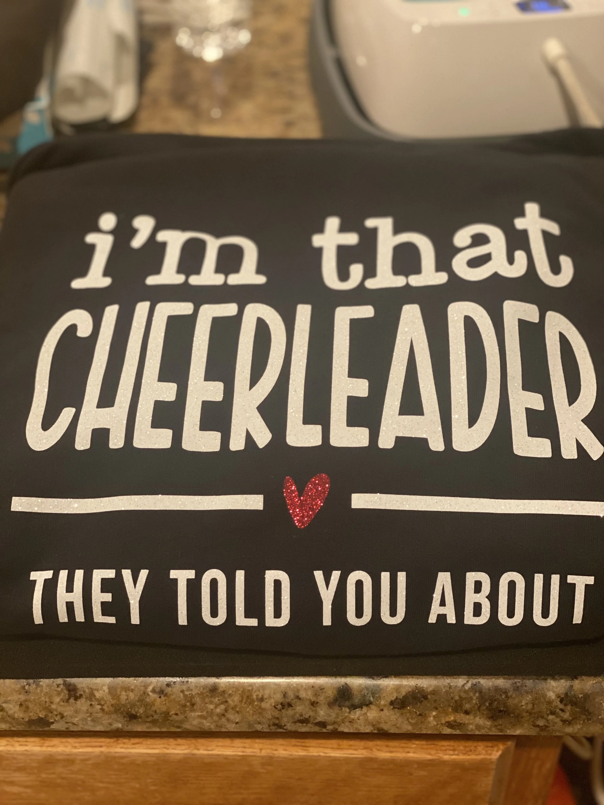 Close-up of a black bag with white text that reads 'I'm that CHEESEHEAD' and a small red glittery heart at the bottom.