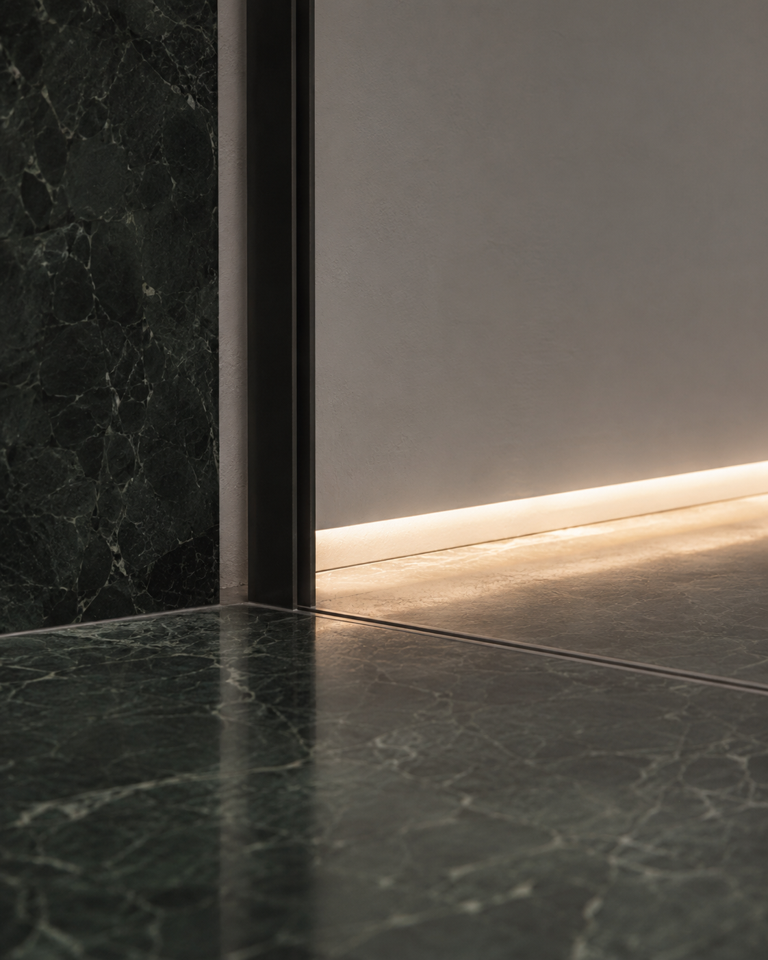 Close-up of an open door with a marble and concrete interior, illuminated by subtle lighting from the floor.