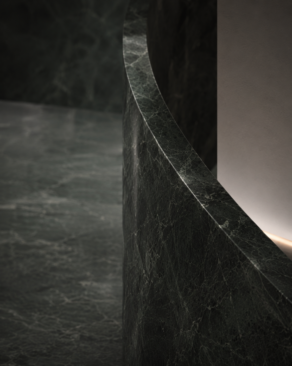 Close-up of a dark green marble surface with a polished finish, showing intricate veining and natural patterns.