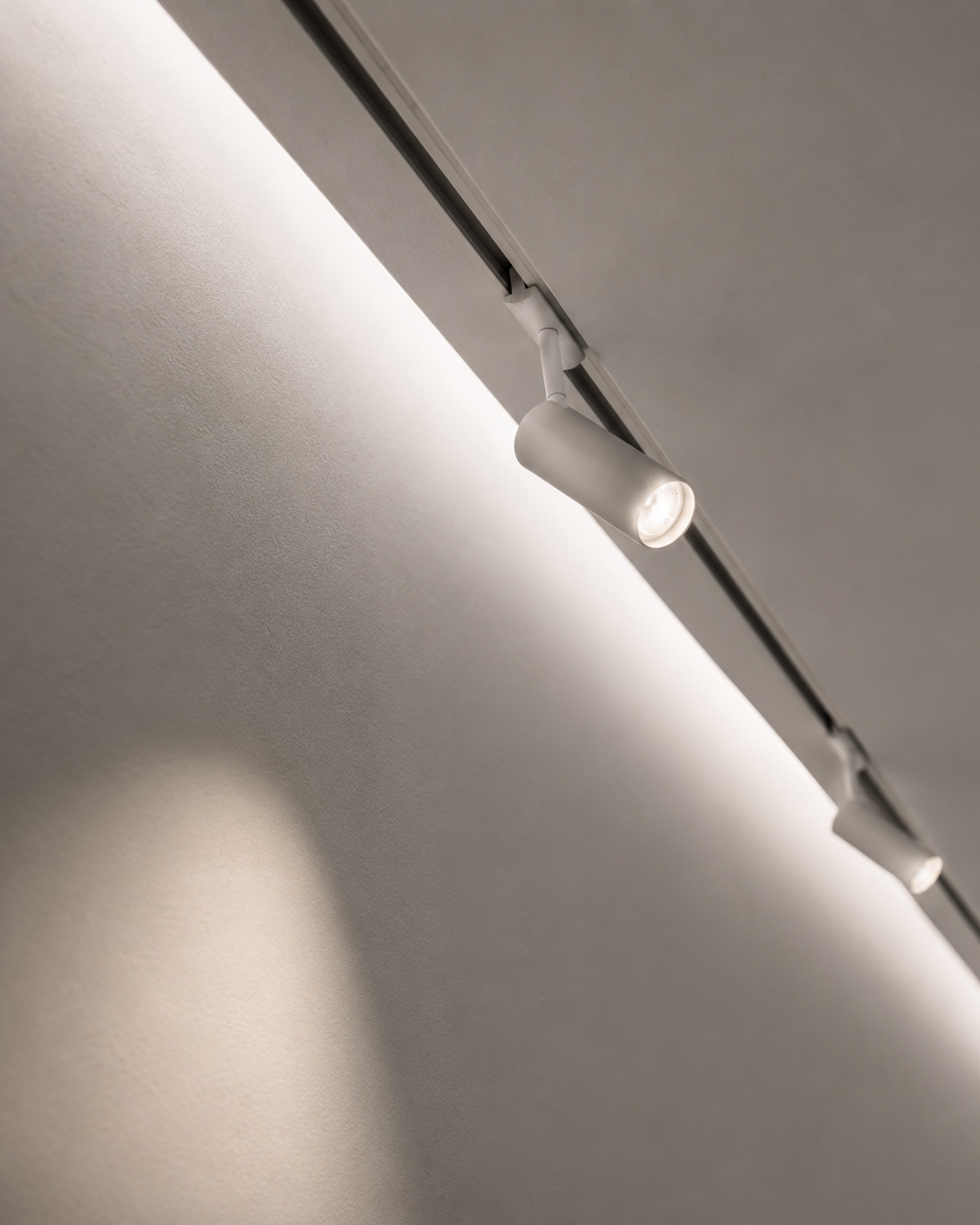 Close-up of ceiling-mounted track lighting with two adjustable spotlights in a room.