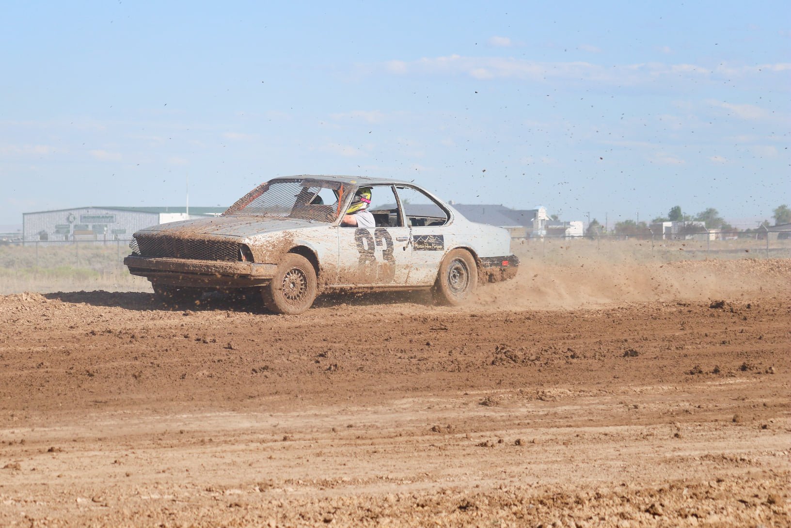 A dirt race car with the number 92 on the side speeding on a dirt track, kicking up dust behind it.