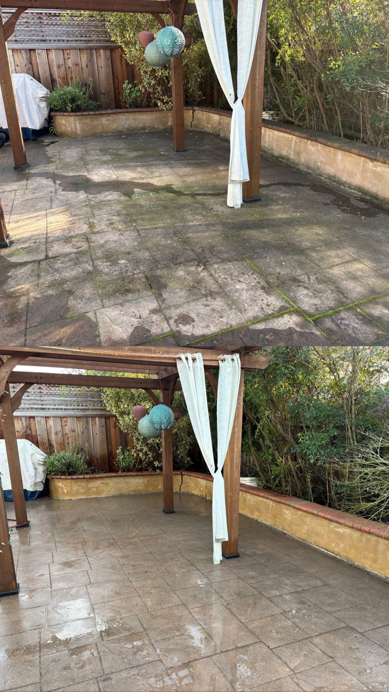 Empty outdoor patio area with wet tile floor, surrounded by a wooden fence and lush greenery, featuring a pergola with hanging lanterns and a white curtain.