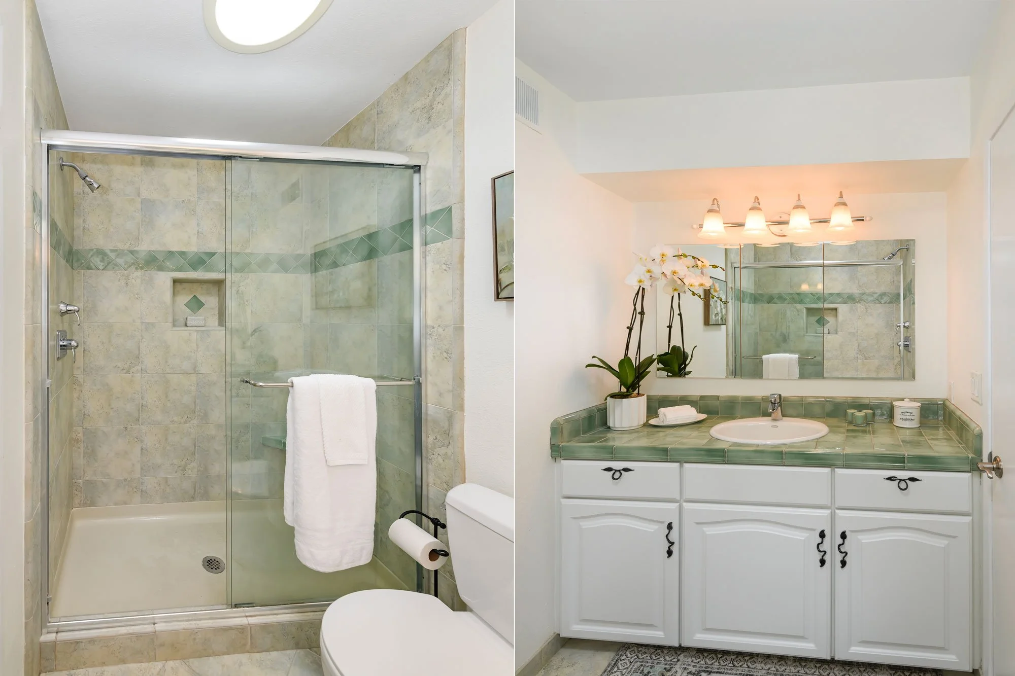 A bathroom split into two sections; on the left side, a shower with glass door, corner niche, and beige tiled walls, with a white towel hanging on a bar. On the right side, a vanity with a green tiled countertop, a white cabinet, a sink, a mirror, an