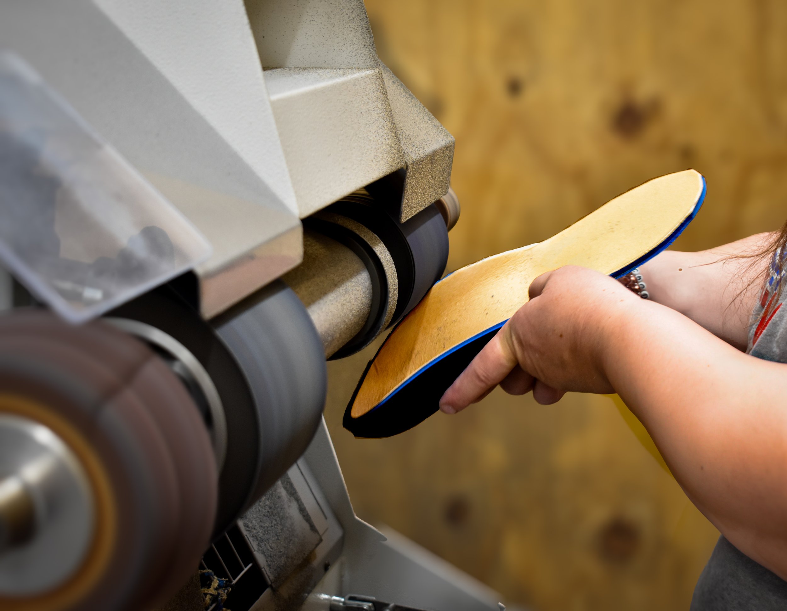 A person using a grinder to shape a custom orthotic mold.