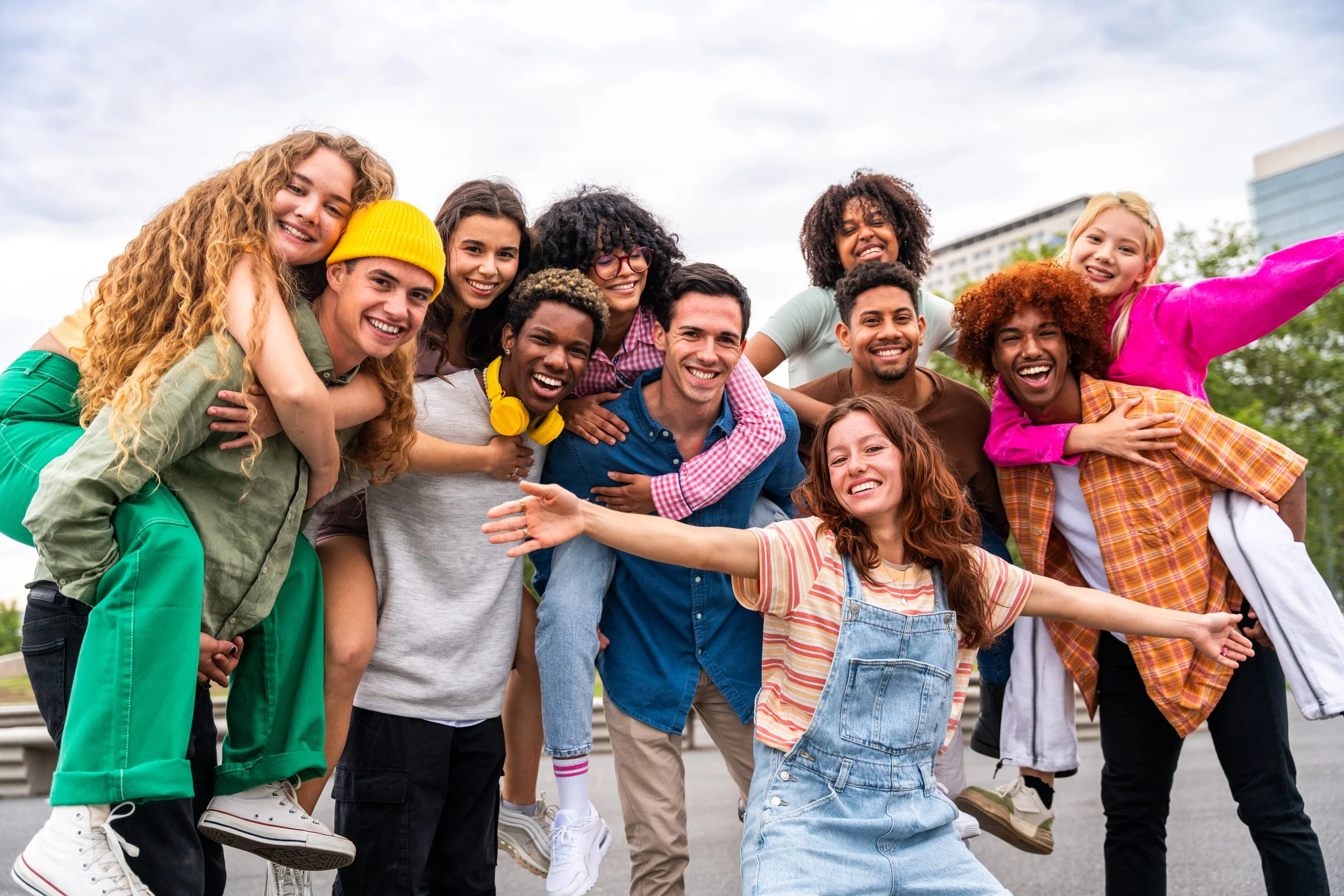 A diverse group of happy young people taking a group selfie outdoors.