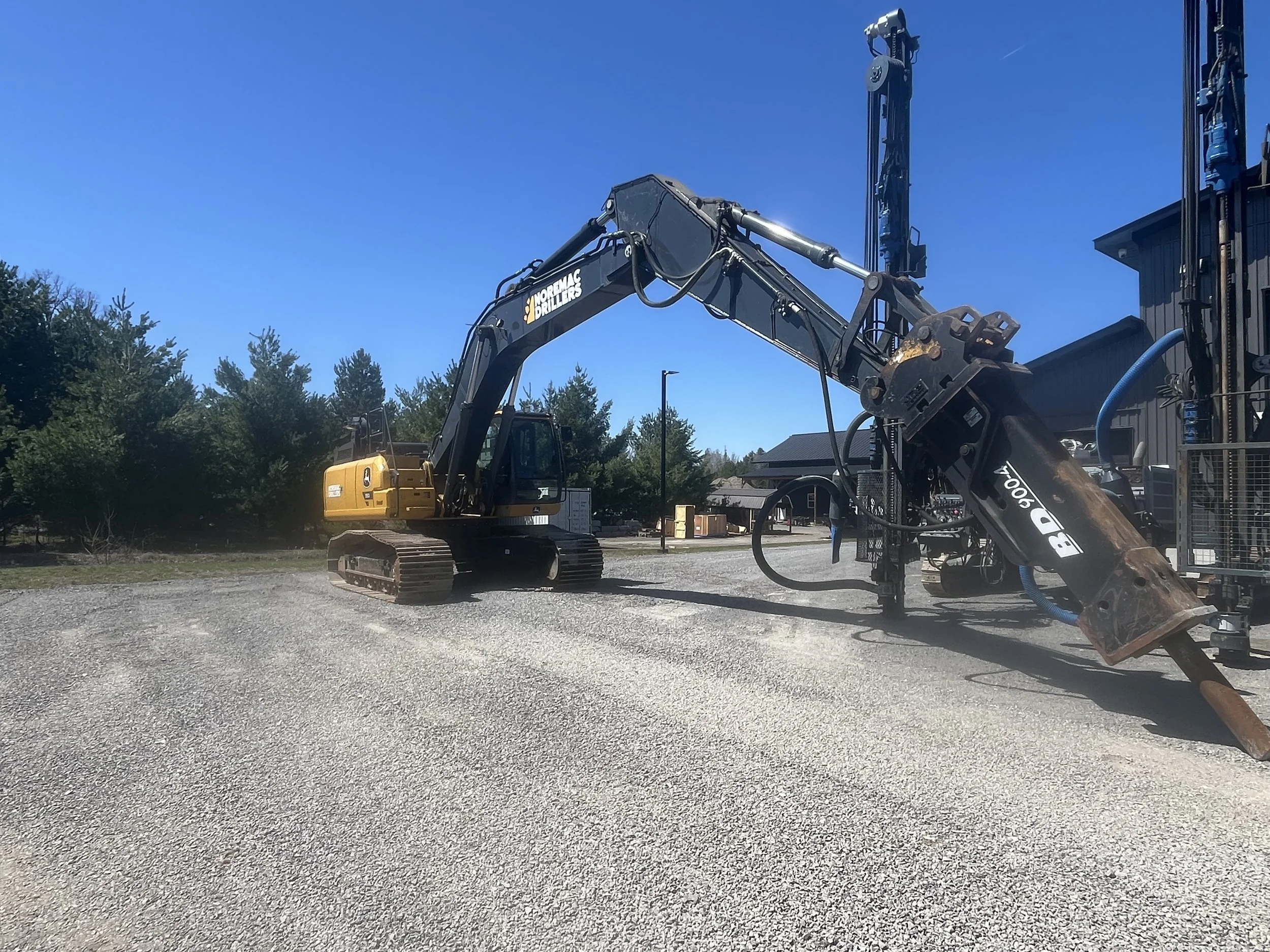 Construction site with a large North American excavator and drilling equipment.