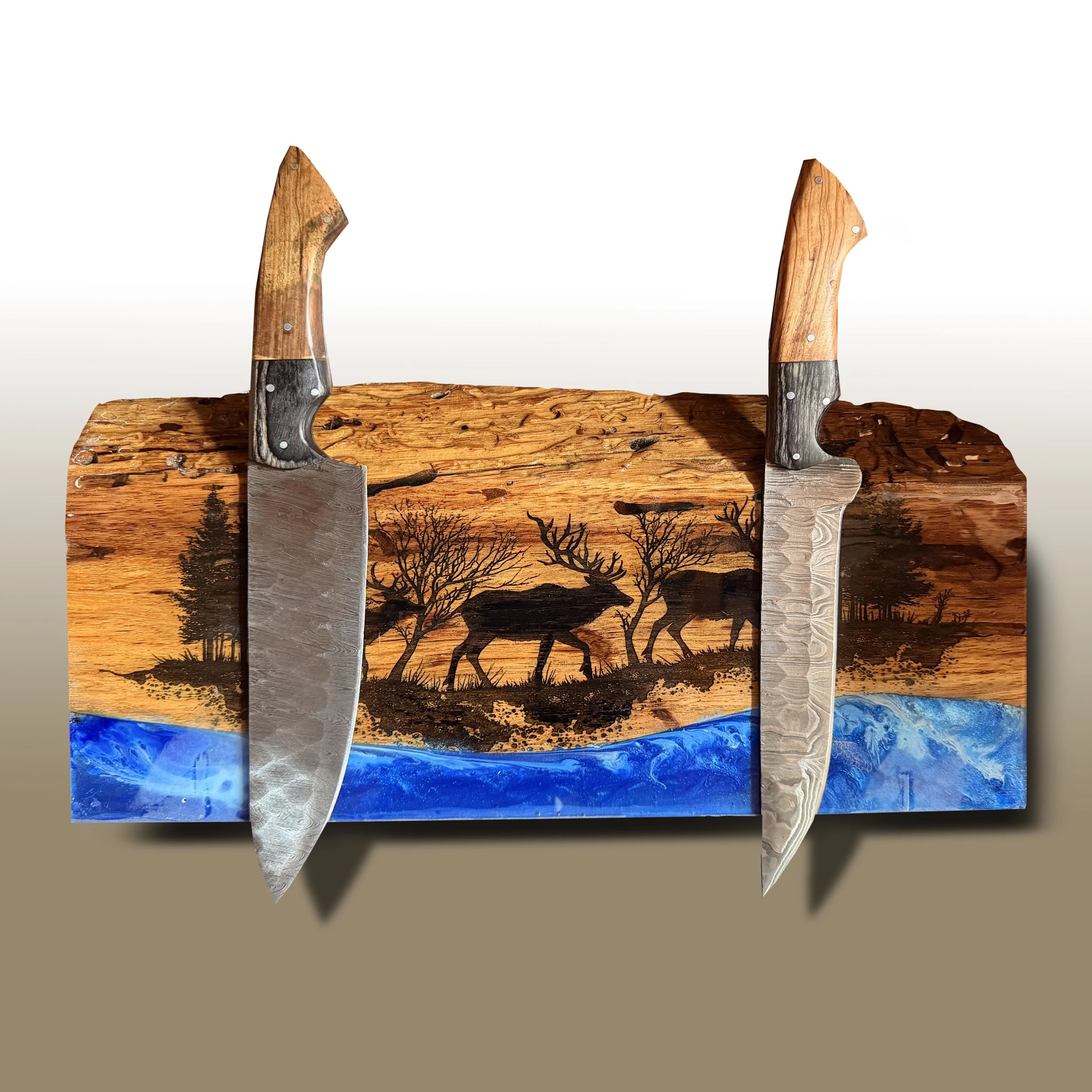 A mixed media artwork featuring a silhouette of African wildlife, including elephants, giraffes, and trees, painted on a wooden panel with a sunset background, and two large curved knives with wooden handles in the foreground.