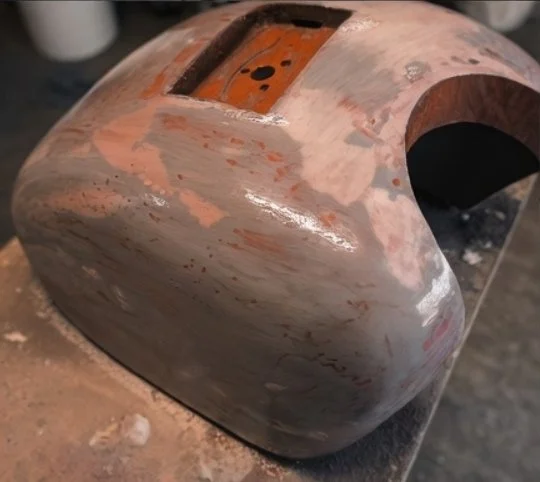 A spherical metallic object with a rectangular opening and a circular cutout, showing signs of sanding or grinding.