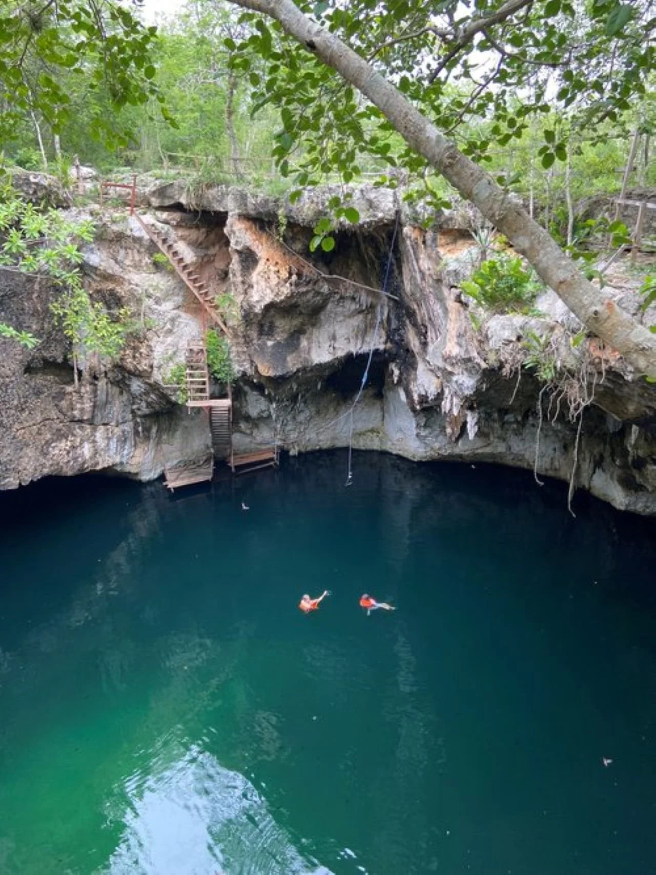 Two people floating in a Sacred Maya Cenote. Off the beaten path. Watering hole deep in the Yucatán jungles.