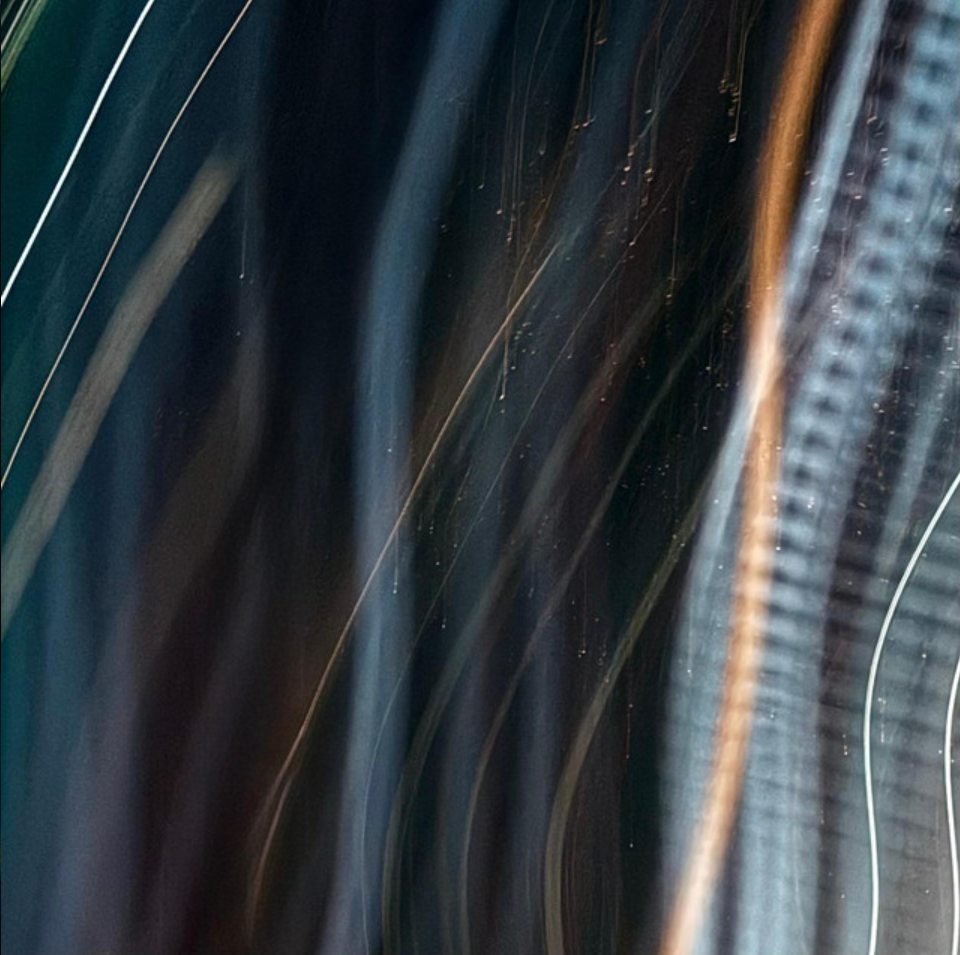 Close-up of a guitar with a shiny black body and a textured fretboard.