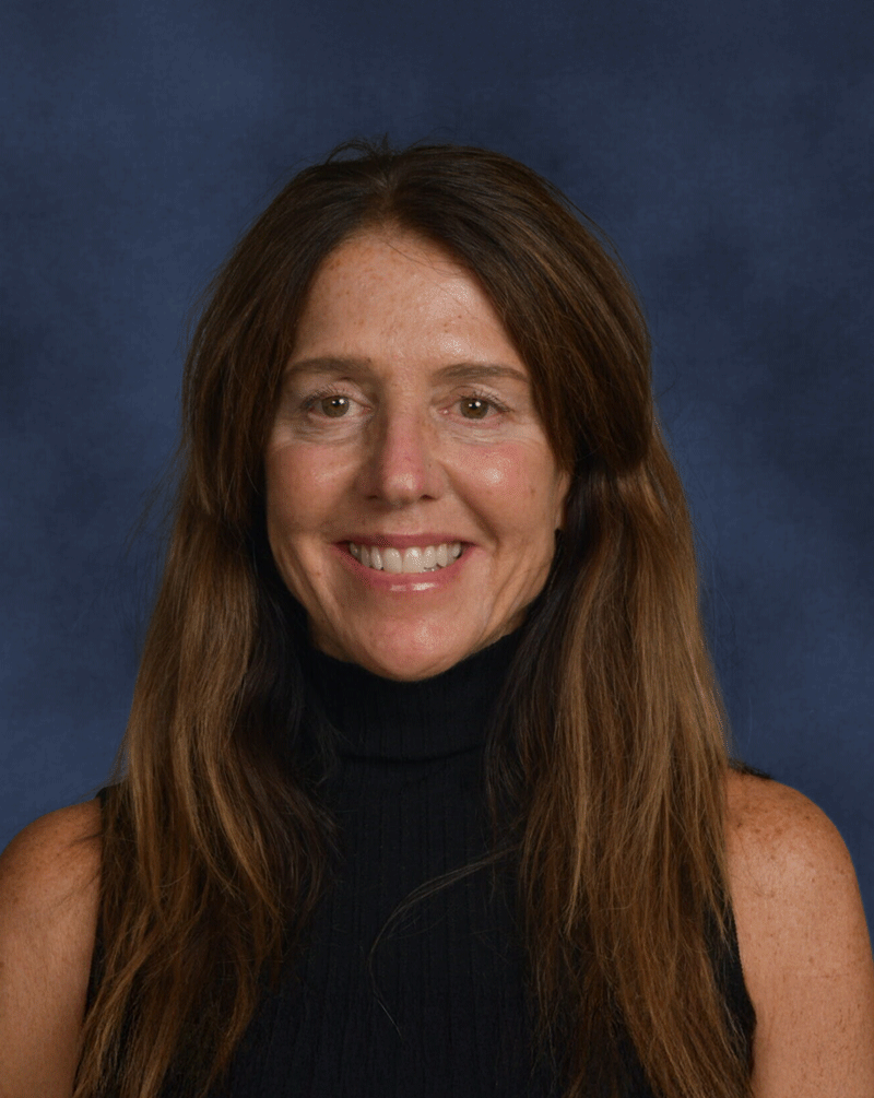Portrait of a woman with long brown hair, wearing a black sleeveless turtleneck, smiling against a blue background.