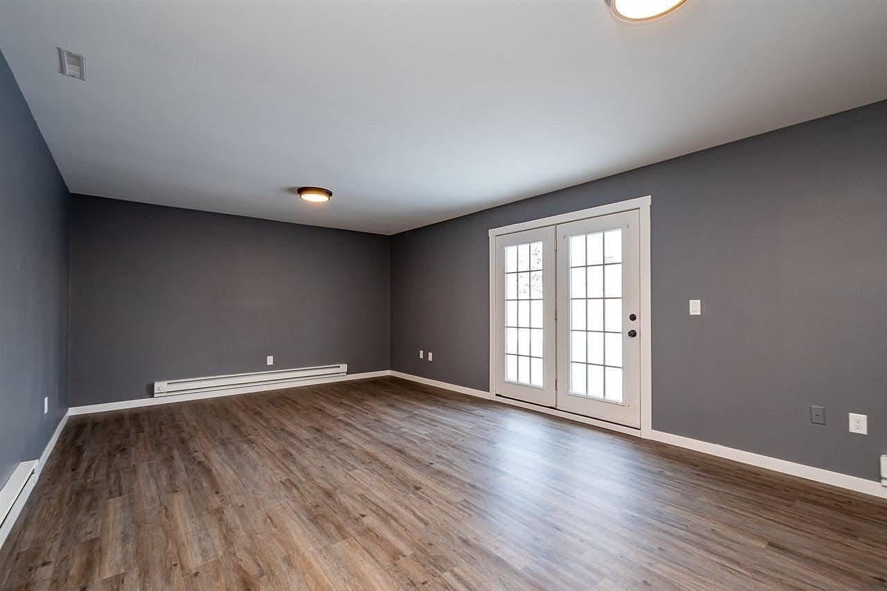 Empty living room with gray walls, hardwood floors, white baseboards, and French doors leading outside. Iowa City. Stecker Home Services. Home Renovations. Iowa City Contractor. 