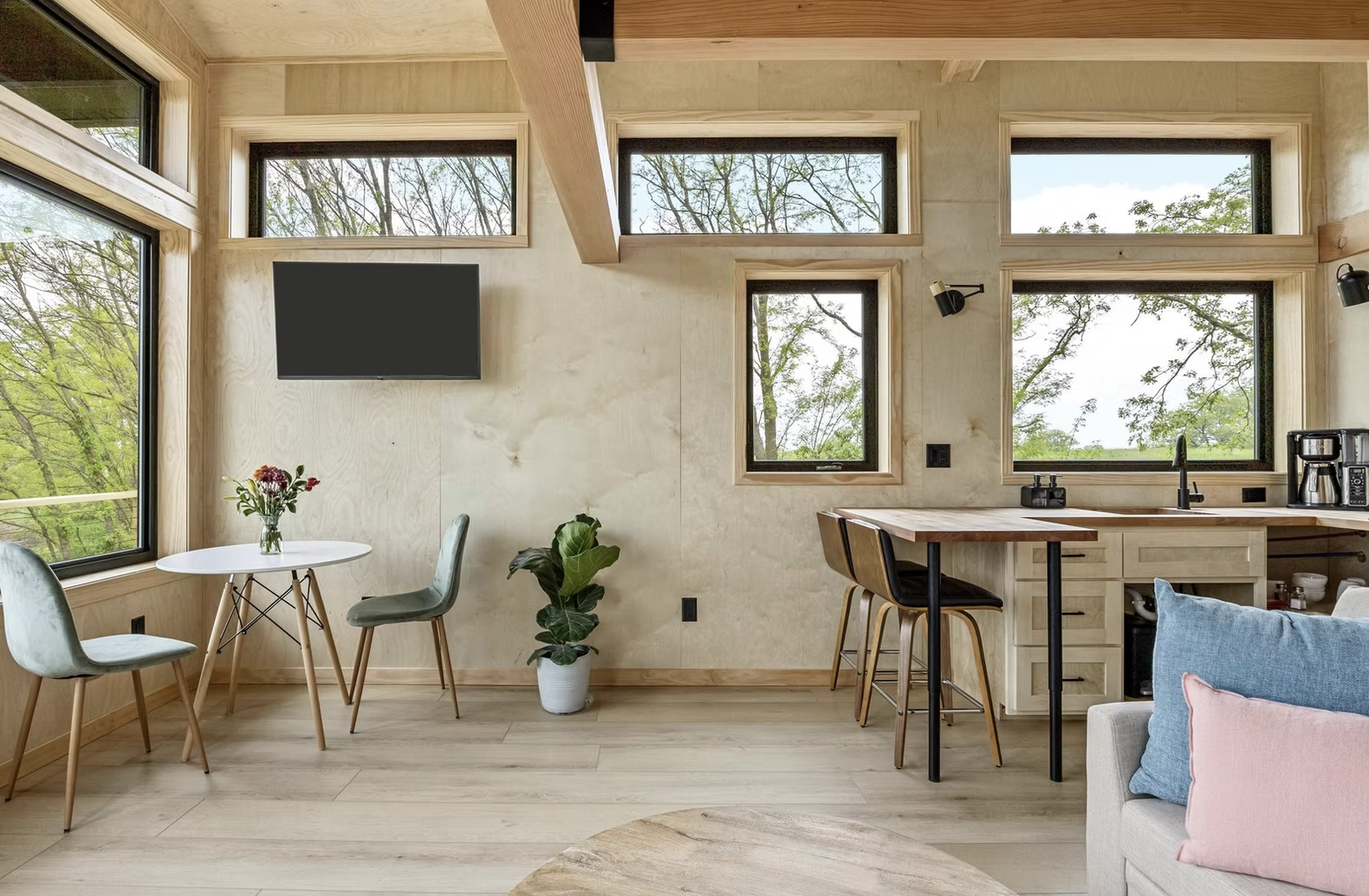 Interior of a modern house with large windows showing trees outside. A small dining table with two chairs is near the window. Iowa City. Stecker Home Services. Home Renovations. Iowa City Contractor. 