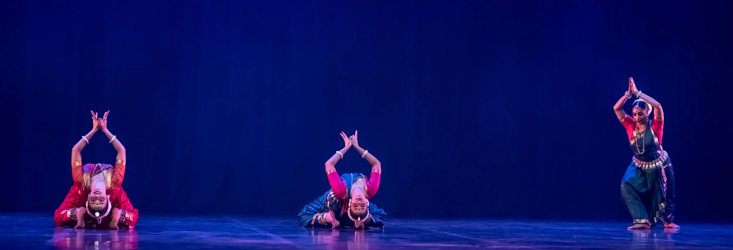 three dancers performing in front of a blue backdrop