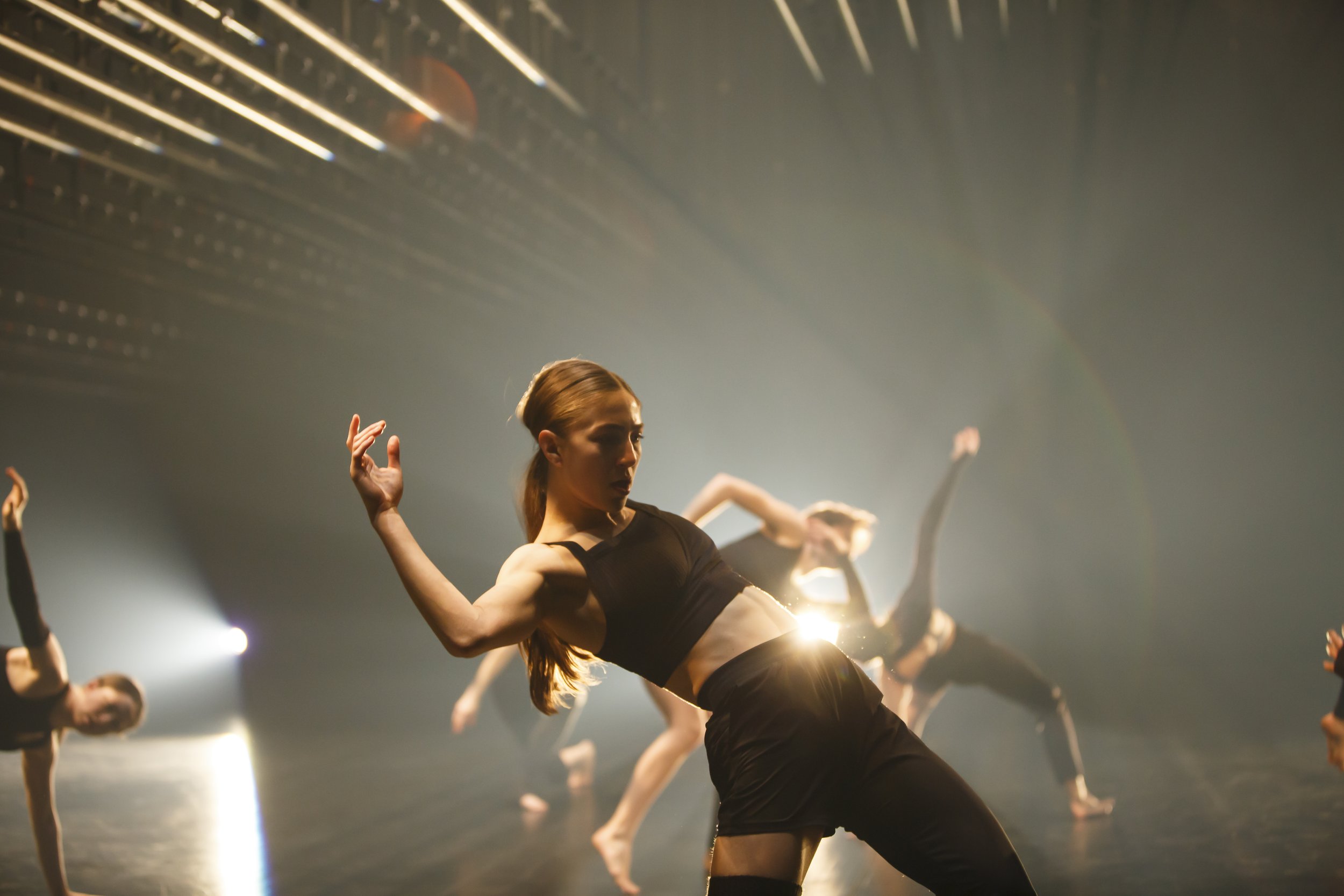 closeup of dancer performing with other dancers performing behind her