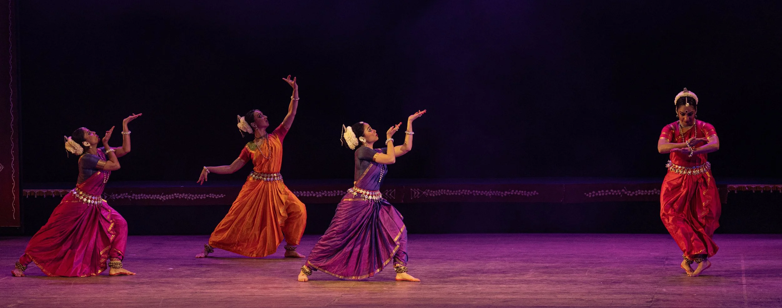 four dancers performing in front of a black backdrop